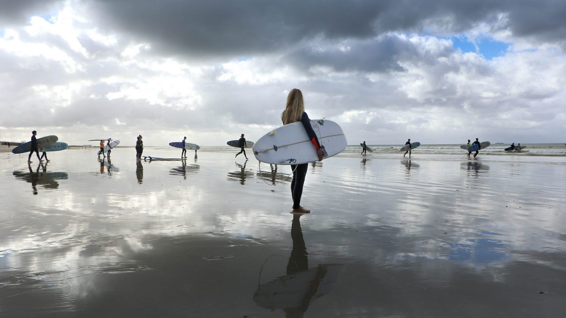 Personas entrando a la playa con tablas de surf