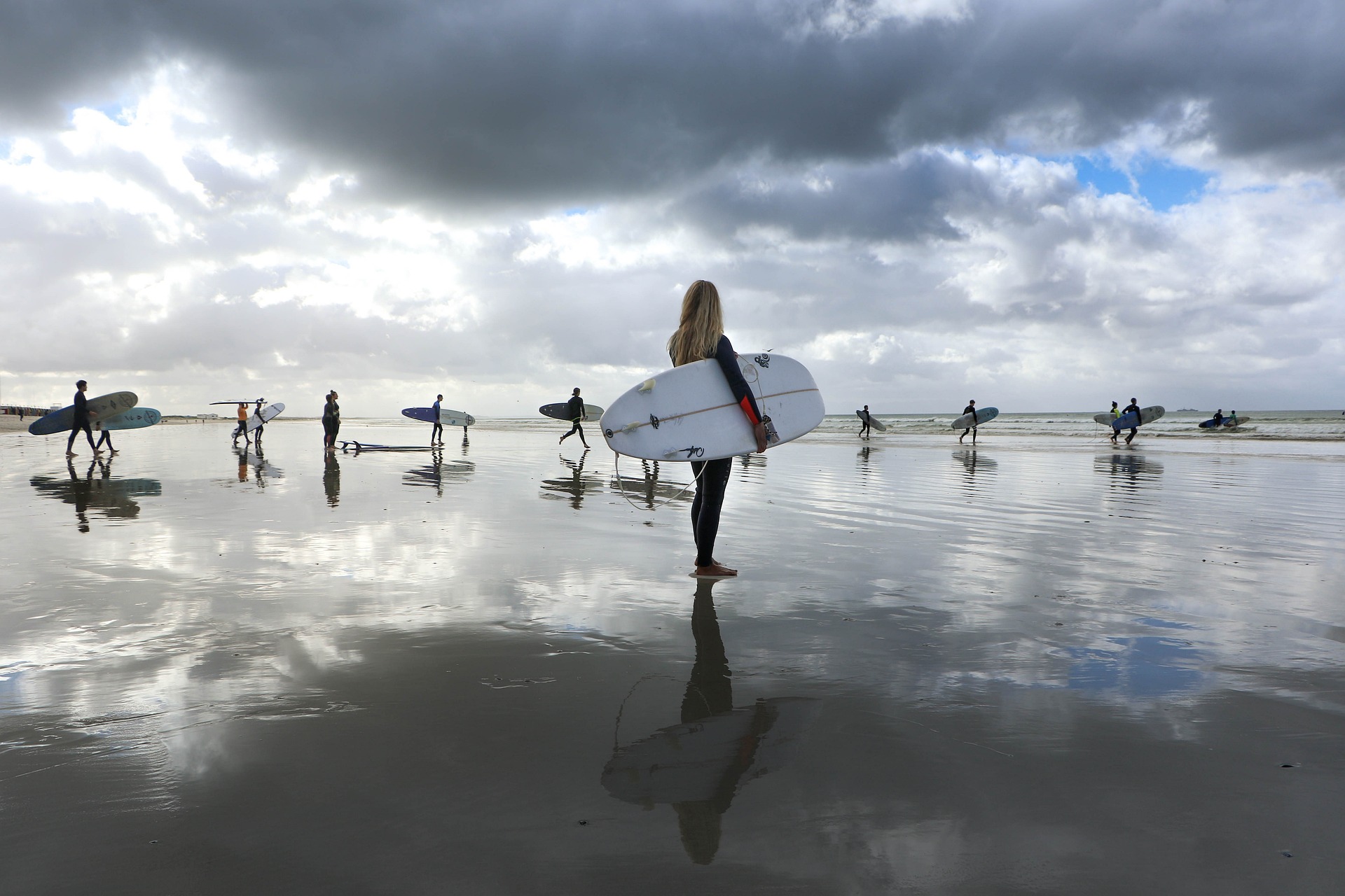 Personas entrando a la playa con tablas de surf